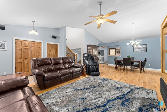 living area featuring a chandelier, lofted ceiling, light wood finished floors, ceiling fan, and stairway