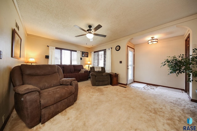 living room with arched walkways, crown molding, a ceiling fan, light carpet, and baseboards