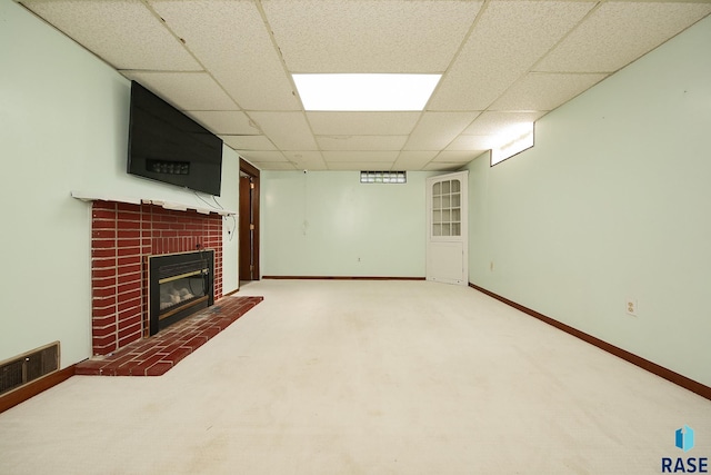 finished basement with a paneled ceiling, a brick fireplace, carpet, and baseboards