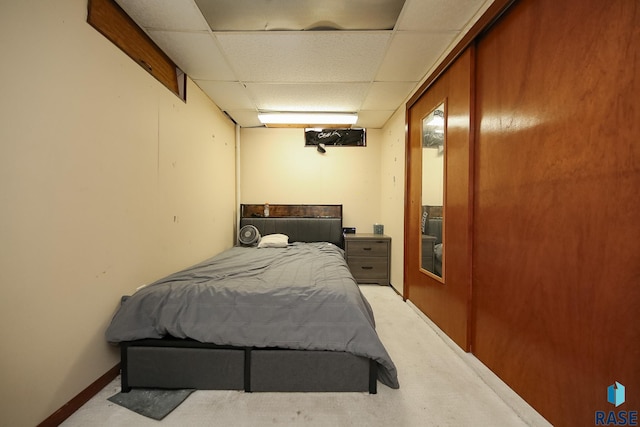 bedroom featuring a paneled ceiling and light carpet