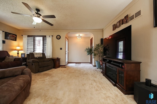 carpeted living room with arched walkways, crown molding, a ceiling fan, and a textured ceiling