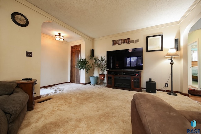 living area with arched walkways, carpet flooring, crown molding, baseboards, and a textured ceiling