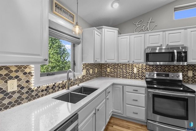 kitchen with stainless steel appliances, a sink, white cabinetry, decorative backsplash, and hanging light fixtures