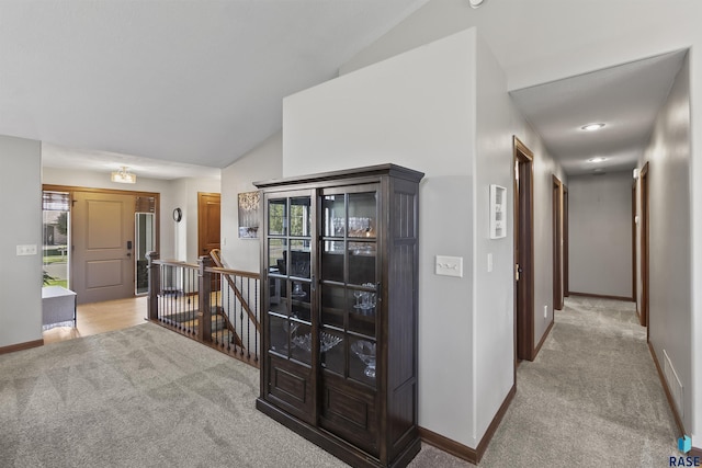 hallway featuring light colored carpet, an upstairs landing, lofted ceiling, baseboards, and plenty of natural light