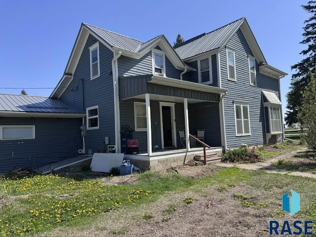 rear view of house featuring a porch and metal roof