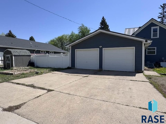 garage featuring fence and a shed
