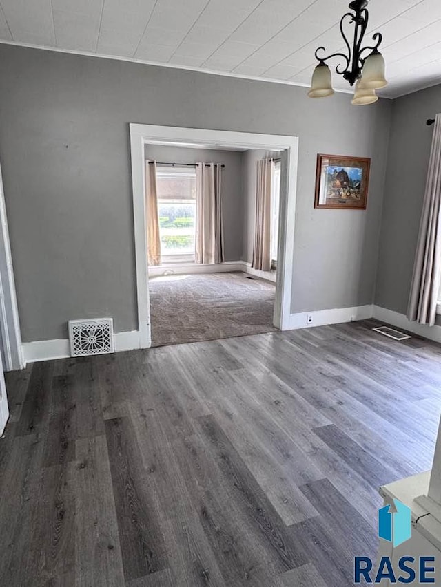 unfurnished dining area featuring wood finished floors, a chandelier, and baseboards