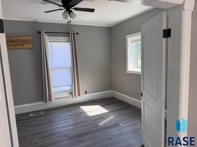 empty room with ceiling fan, baseboards, wood finished floors, and ornamental molding