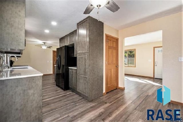kitchen with ceiling fan, freestanding refrigerator, a sink, wood finished floors, and baseboards