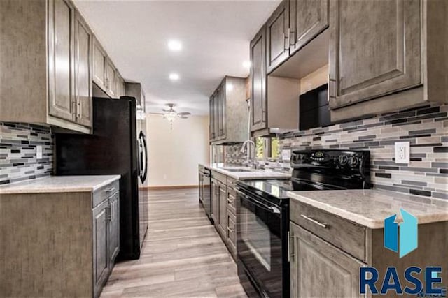 kitchen featuring black appliances, a sink, a ceiling fan, tasteful backsplash, and baseboards