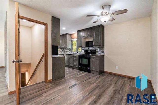 kitchen with black appliances, wood finished floors, light countertops, tasteful backsplash, and baseboards