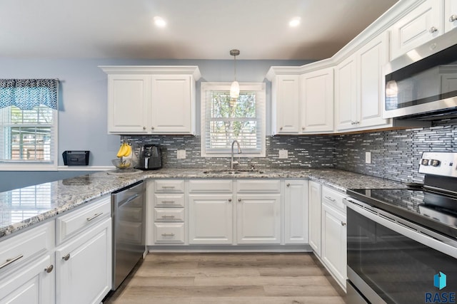 kitchen with stainless steel appliances, a sink, plenty of natural light, white cabinetry, and recessed lighting