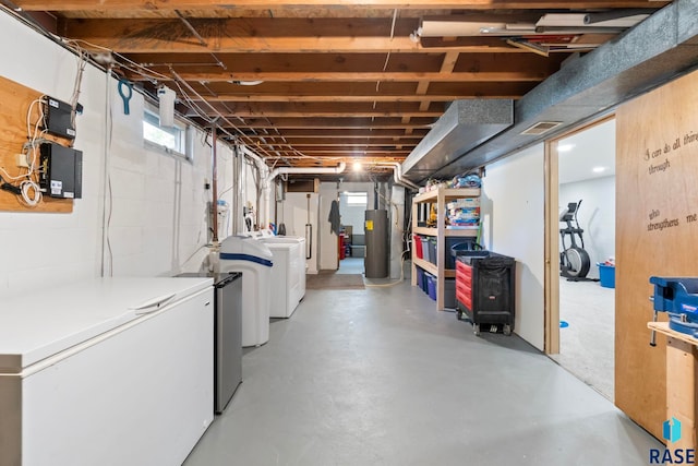 below grade area featuring washing machine and clothes dryer, water heater, and white fridge