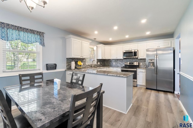 kitchen featuring stainless steel appliances, light wood finished floors, decorative backsplash, light stone countertops, and recessed lighting