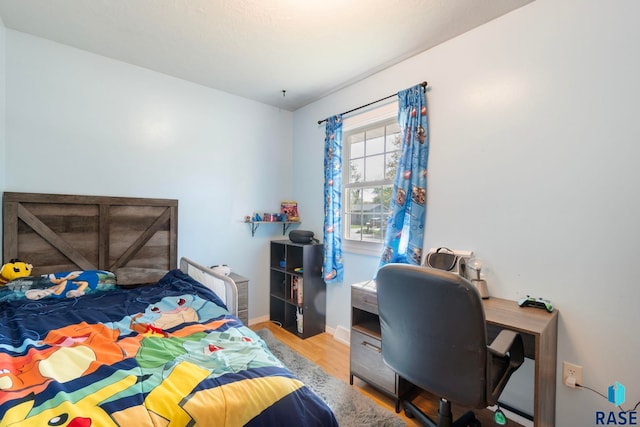 bedroom with wood finished floors, baseboards, and an office area