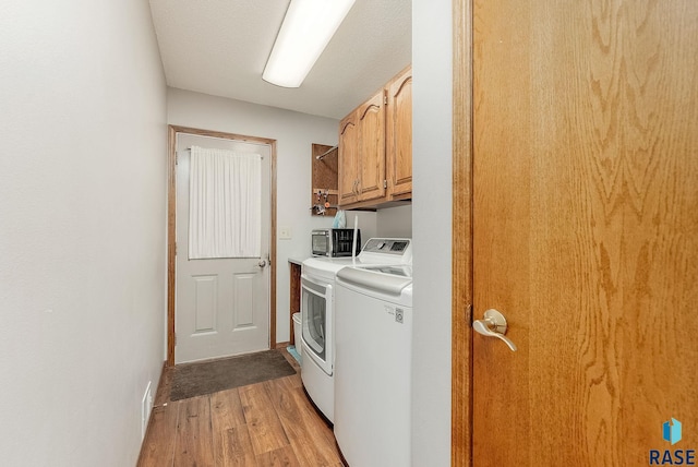 washroom featuring cabinet space, light wood-style flooring, and washing machine and dryer