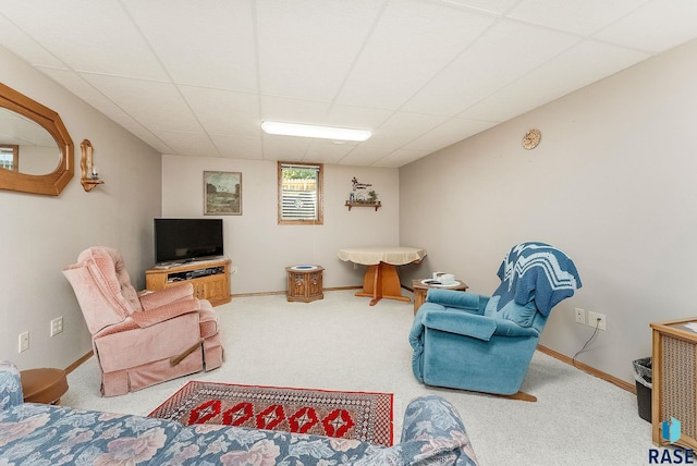 carpeted living area featuring a paneled ceiling and baseboards