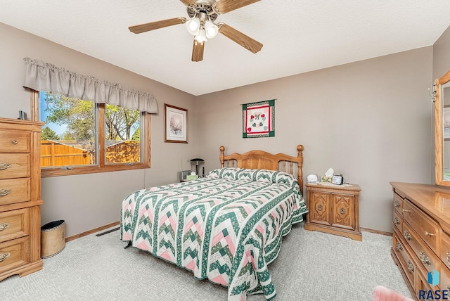 bedroom featuring light carpet, baseboards, and ceiling fan