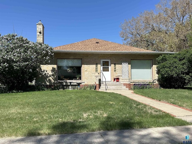 bungalow-style house featuring entry steps, a front yard, roof with shingles, and a chimney