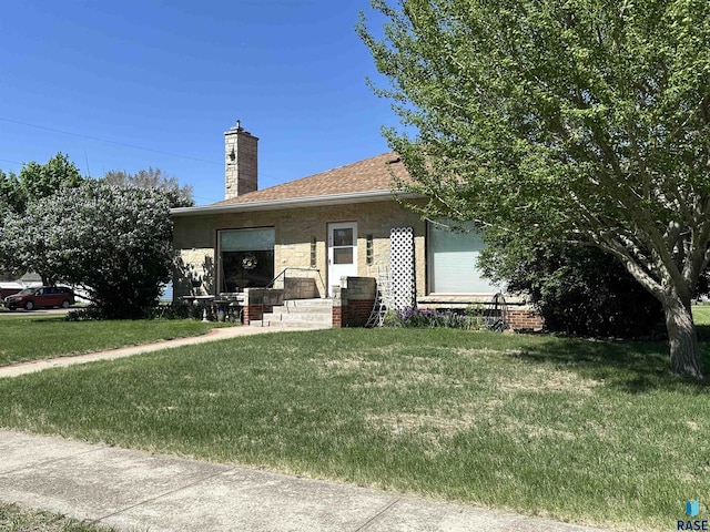 rear view of house with a chimney and a lawn
