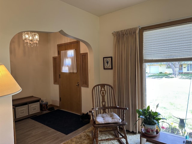 entrance foyer with arched walkways, wood finished floors, and a chandelier