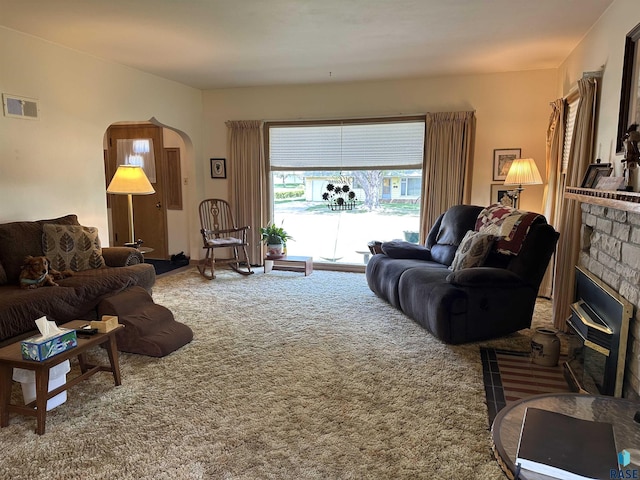 living area with carpet flooring, arched walkways, and a glass covered fireplace