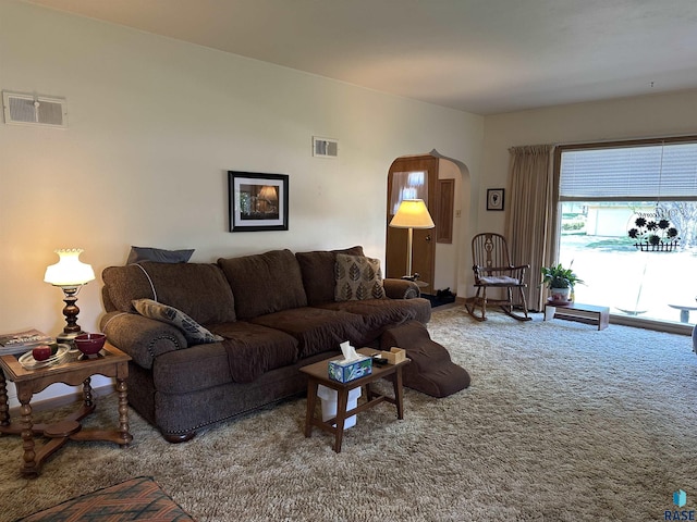 carpeted living area featuring arched walkways