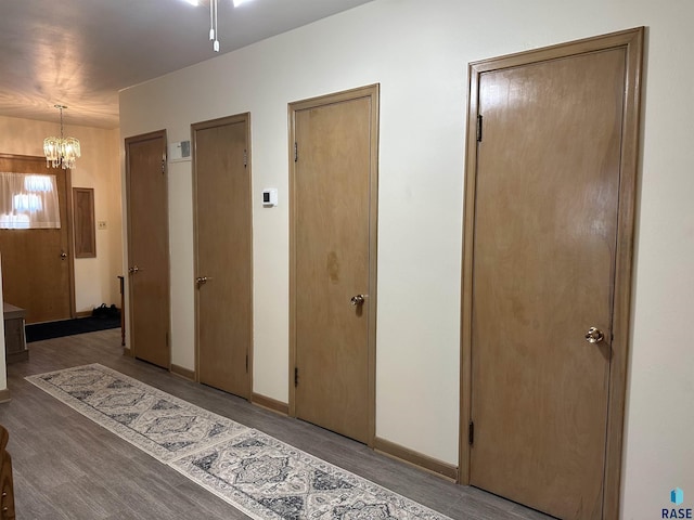 hallway with wood finished floors, a chandelier, and baseboards