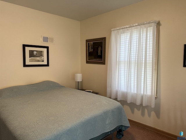 bedroom with dark carpet and baseboards