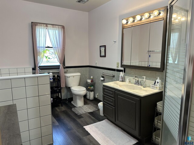bathroom with tile walls, wood finished floors, toilet, a wainscoted wall, and vanity