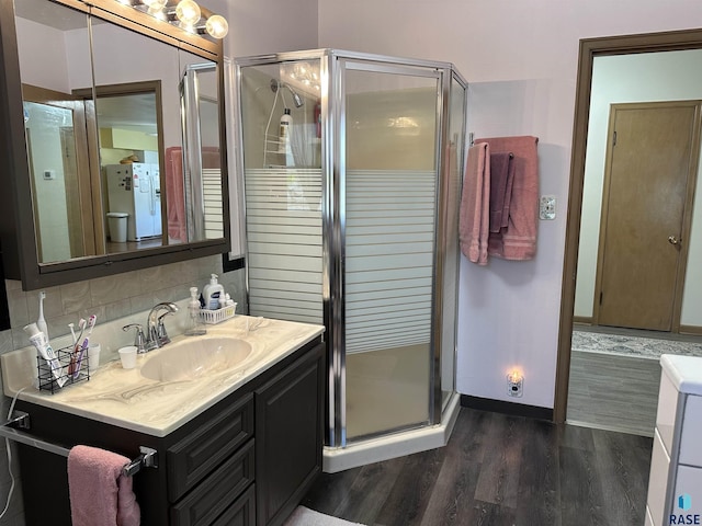 full bath with a stall shower, vanity, wood finished floors, and baseboards