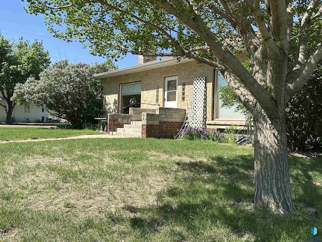 view of front of property with a front yard, a chimney, and stone siding