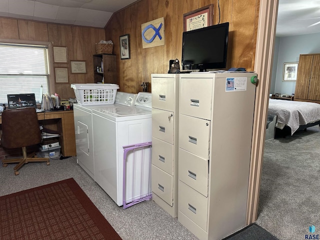 clothes washing area with separate washer and dryer, light colored carpet, and wooden walls