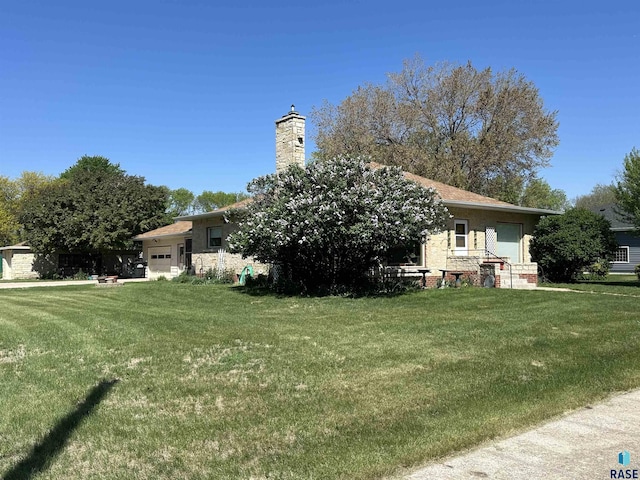back of property with a garage, a lawn, and a chimney