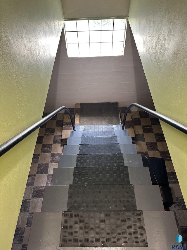 stairs with tile patterned floors and a textured wall