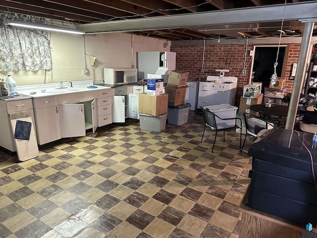unfinished basement with tile patterned floors, brick wall, and a sink