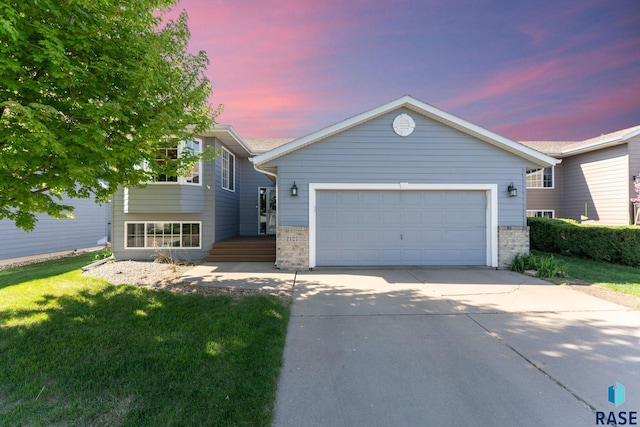 view of front facade featuring concrete driveway, brick siding, a garage, and a front yard