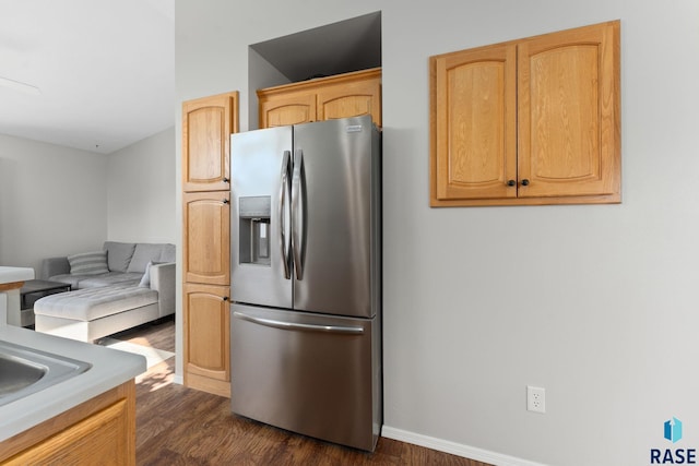 kitchen featuring stainless steel fridge with ice dispenser, dark wood-style floors, light countertops, light brown cabinetry, and baseboards