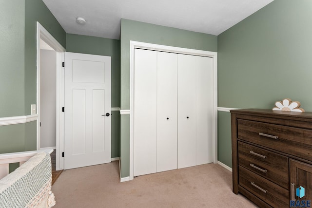bedroom with light colored carpet, a closet, and baseboards