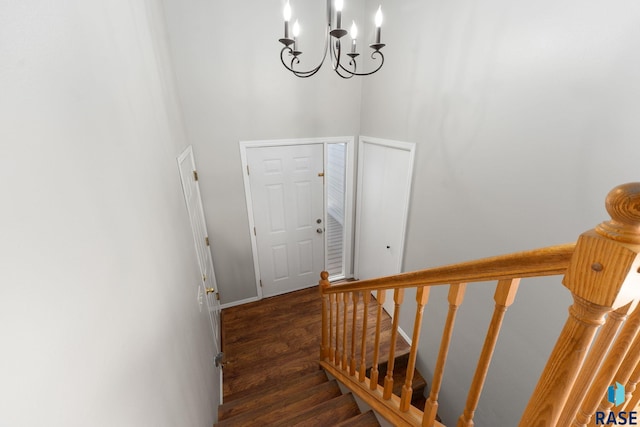 stairway with a chandelier, wood finished floors, and baseboards