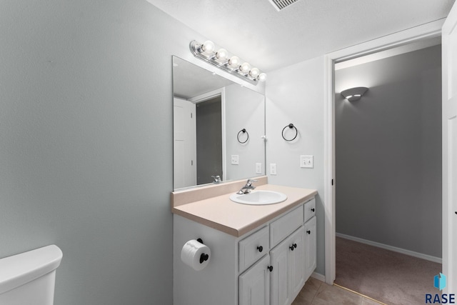 bathroom featuring toilet, vanity, and baseboards