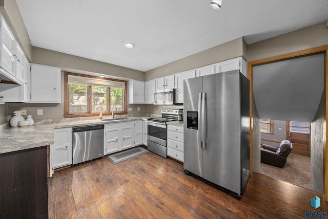 kitchen with stainless steel appliances, a sink, white cabinets, dark wood-type flooring, and recessed lighting