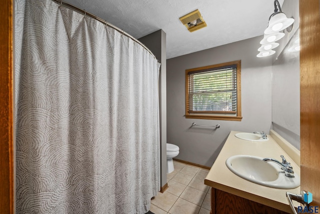 bathroom featuring toilet, tile patterned flooring, double vanity, and baseboards