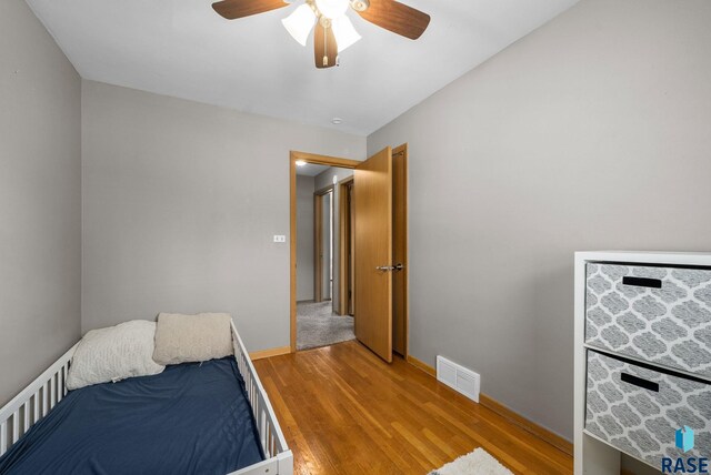 bedroom featuring light wood finished floors, baseboards, and a ceiling fan