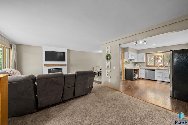 living area featuring a fireplace, wood finished floors, carpet flooring, and baseboards
