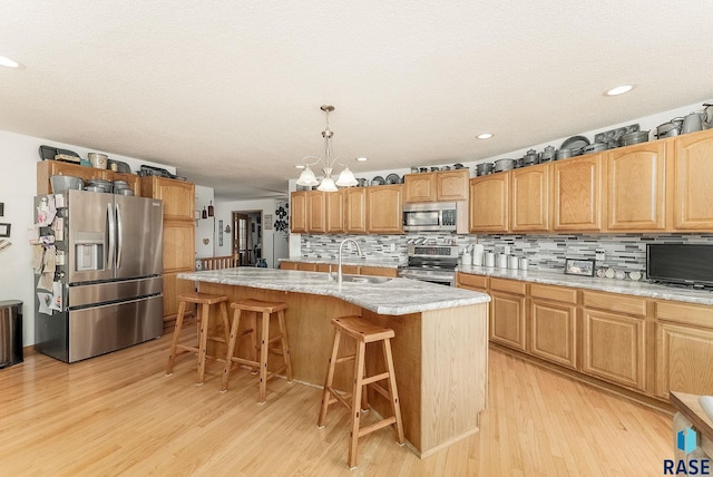 kitchen featuring appliances with stainless steel finishes, a sink, decorative backsplash, light wood-style floors, and recessed lighting