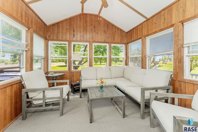 sunroom featuring lofted ceiling, carpet flooring, healthy amount of natural light, and wooden walls