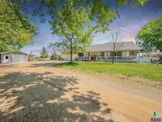 ranch-style home with covered porch, dirt driveway, a front yard, and a garage