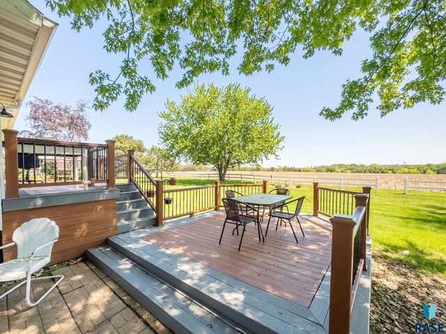 wooden terrace with a lawn, outdoor dining space, and a view of countryside