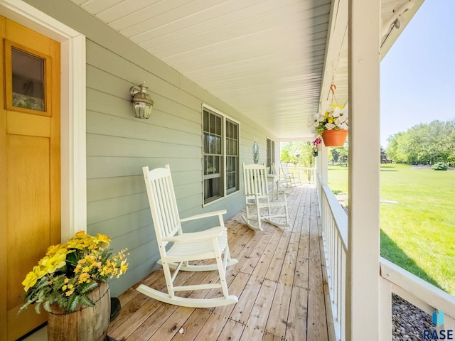wooden deck featuring covered porch and a lawn